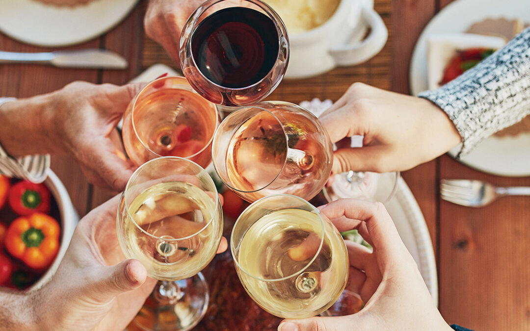 Thanksgiving, toast and wine with hands of people at home dining room table for celebration from above. Dinner party, food and roast with friends in apartment together for cheers or social gathering