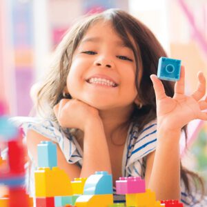 Little Girl Holding Construction Blocks in Hand at Home