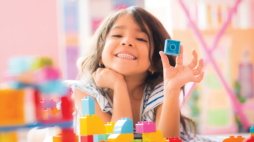 Little Girl Holding Construction Blocks in Hand at Home