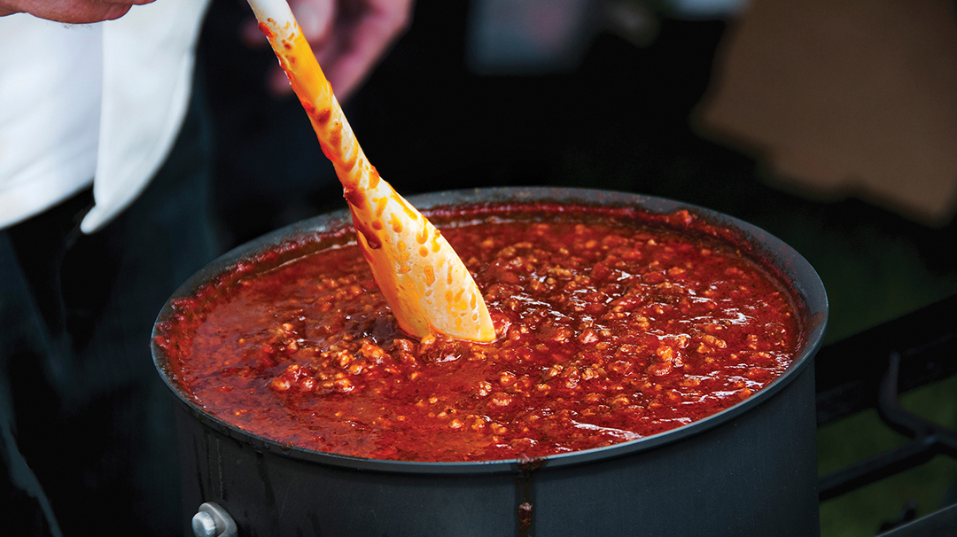 Cook Stirring a Simmering Pot of Spicy Chili